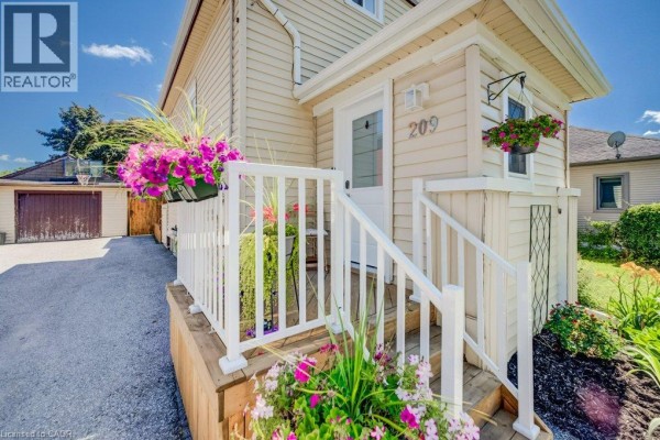 Close-up of the front entrance with white railings, steps, and blooming flowers. - 209 Belleview Avenue, Kitchener