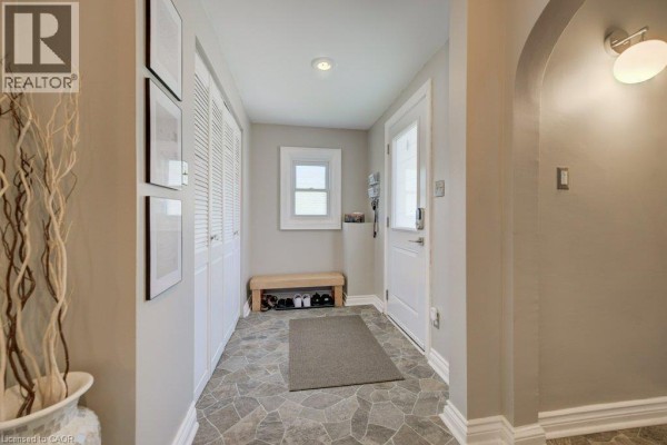 Interior entryway with tiled floor, closet doors, bench with shoes, and a window. - 209 Belleview Avenue, Kitchener