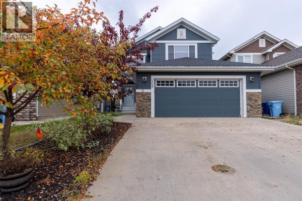 Driveway and front exterior of a dark grey house with a large garage door. - 209 Blackburn Drive, Fort Mcmurray