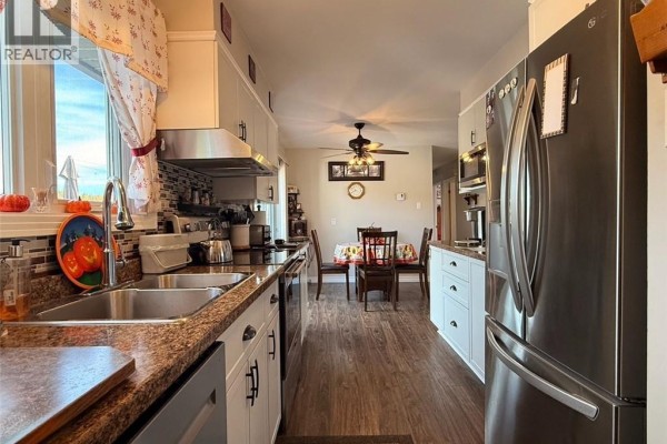 Kitchen with granite countertops, stainless steel appliances, and a dining area with a table and chairs. - 209 Centennial Heights Street, Dalhousie