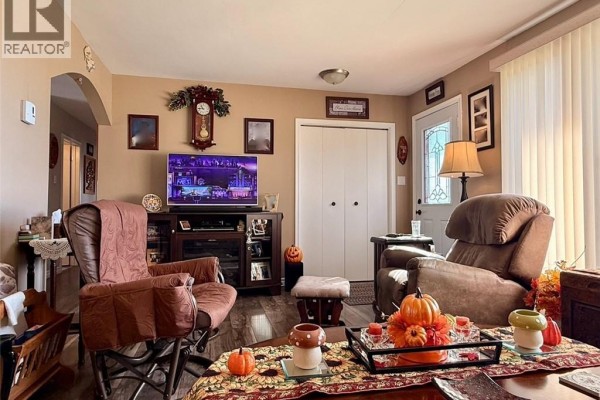 Living room with two recliners, a television, a clock, a door, and seasonal decorations on the coffee table. - 209 Centennial Heights Street, Dalhousie