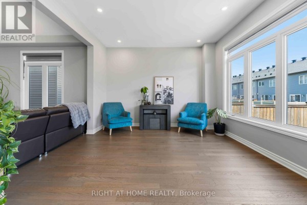 Living room with teal accent chairs, dark sofa, and large windows - 209 Quarter Horse Street Ottawa