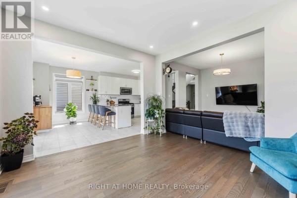 Open-concept living room with island kitchen, sectional sofa, and hardwood floors - 209 Quarter Horse Street Ottawa