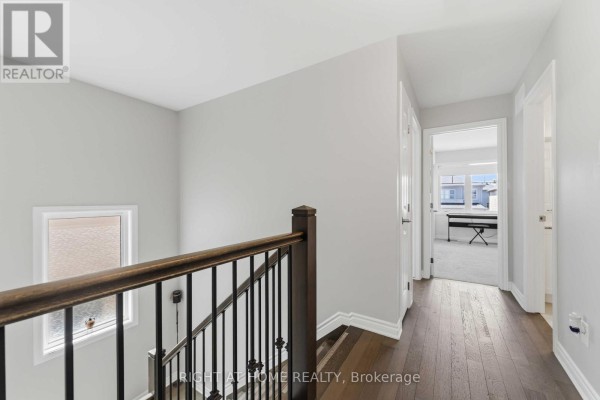Hallway with hardwood floors and dark wood banister - 209 Quarter Horse Street Ottawa