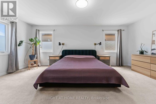 Queen bed with purple quilt, nightstands, and wall sconces in a bedroom - 209 Quarter Horse Street Ottawa