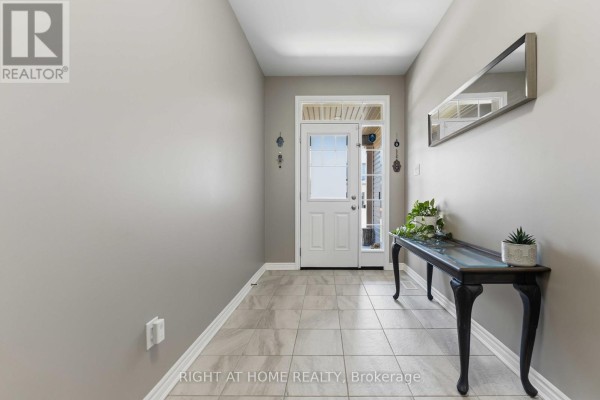 Interior entryway with light gray walls, tiled floor, a console table, and a mirrored wall. - 209 Quarter Horse Street, Ottawa