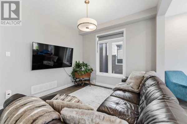 Living room with sectional sofa, mounted TV, and large window - 209 Quarter Horse Street Ottawa