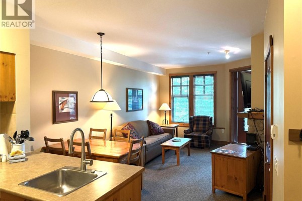 Living and dining area with sofa, chairs, dining table, and kitchen island. - 2090 Summit Drive Unit# 106, Panorama