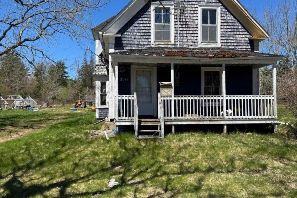 Aerial view showing two houses, a greenhouse, and surrounding trees on a grassy property beside a road. - 2091 Highway 203, Kemptville