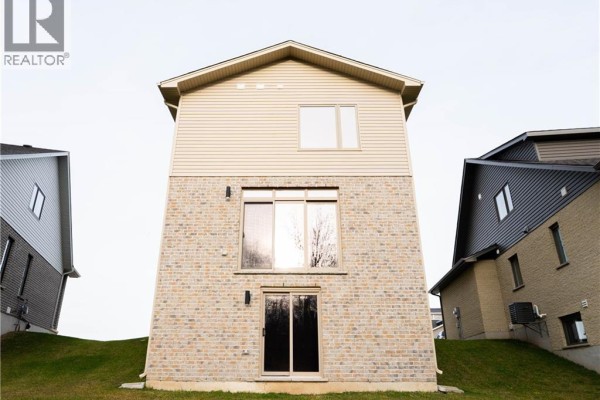 Rear view of a modern house with brick lower level and vinyl siding upper level. - 2092 Evans Boulevard, London