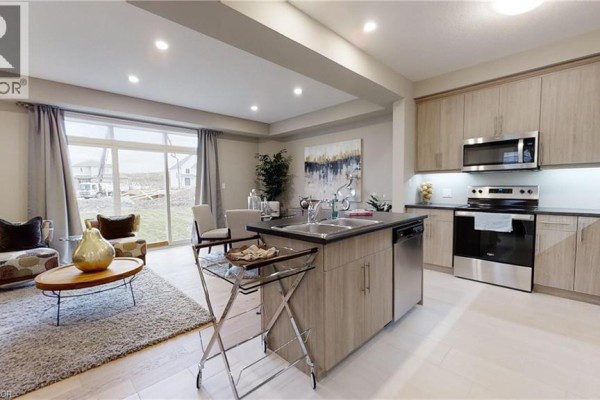 Open concept living area and kitchen with island, stainless steel appliances, and large sliding doors. - 2092 Evans Boulevard, London