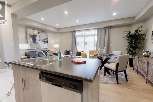 Kitchen island with sink and dishwasher, adjacent dining area with table and chairs, and living room. - 2092 Evans Boulevard, London