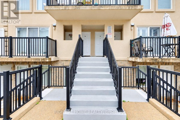 Exterior view of a townhouse complex entrance with concrete stairs and black railings. - 2095 - 55 George Appleton Way, Toronto
