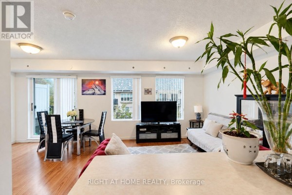 Living and dining area with wood floors, glass-top dining table, and beige sofa. - 2095 - 55 George Appleton Way, Toronto