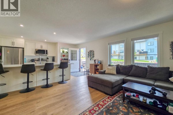 Open concept living room and kitchen with a large sectional sofa and island seating. - 2096 Pine Tree Lane Unit# 39, Invermere