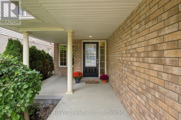 Covered front porch with white columns, beige brick exterior, and black front door with glass. - 2097 Stornoway Street, Oshawa