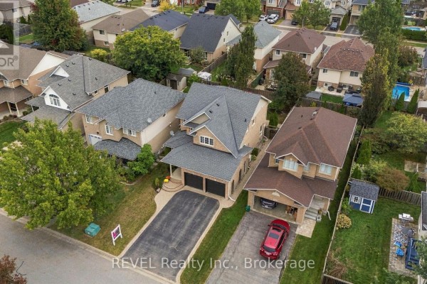 Aerial view of a brick two-story house with a double garage, driveway, and neighboring properties. - 2097 Stornoway Street, Oshawa