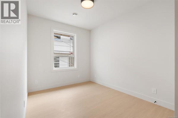 Empty room with white walls, light wood floors, and a window overlooking the exterior. - 2098 Kingbird Dr, Langford