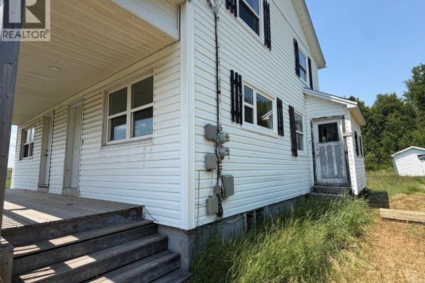 Side view of a white house showing a porch with wooden steps and electrical meters on the exterior. - 2099-2101 Champlain Street, Dieppe