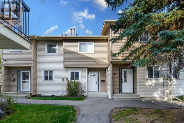 Front exterior of townhouse units with beige and white siding. - 21, 2519 38 Street Ne, Calgary
