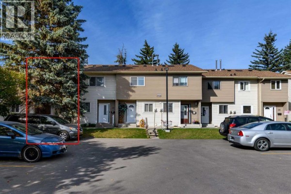Townhouse units with beige and white siding and parking lot. - 21, 2519 38 Street Ne, Calgary