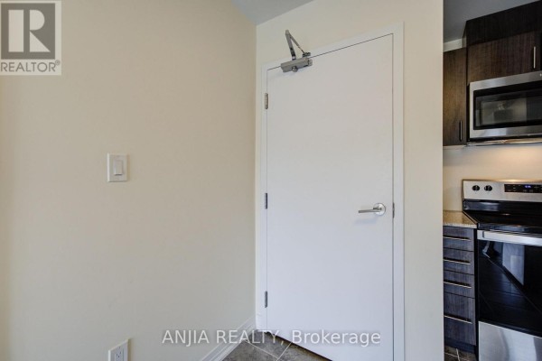 Interior view of a kitchen with stainless steel appliances and dark wood cabinets. - 21 - 235 Mclevin Avenue, Toronto
