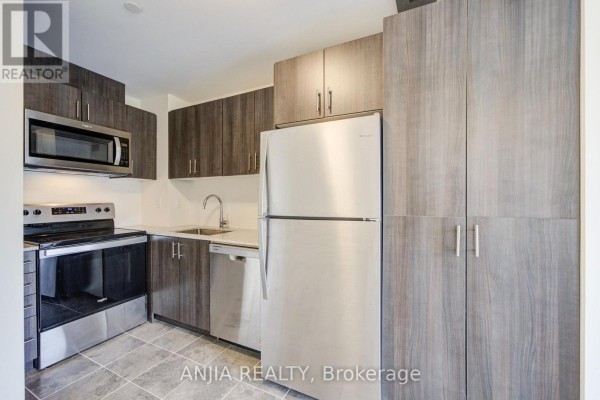 Contemporary kitchen with stainless steel refrigerator, dark wood cabinets, and tiled floor. - 21 - 235 Mclevin Avenue, Toronto