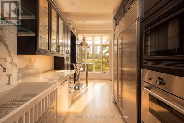 Modern kitchen with stainless steel appliances, marble backsplash, and a view of trees. - 21 - 260 Russell Hill Road, Toronto