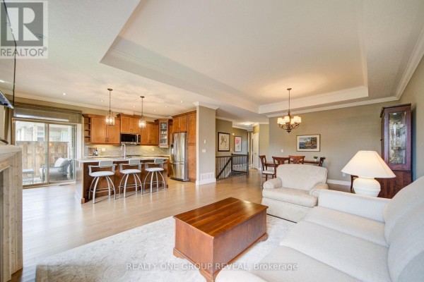 Open concept living and dining area with a kitchen island, light wood cabinets, and a staircase. - 21 - 30 Cedar Street, Brant
