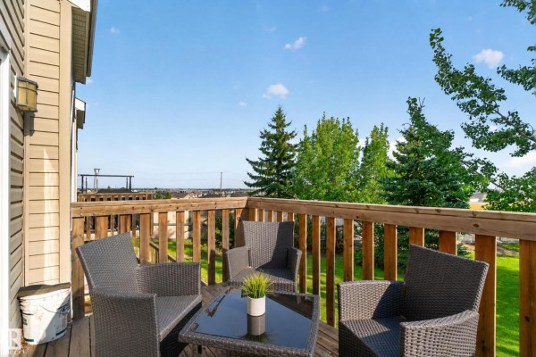 Wooden deck with four chairs and a table, overlooking a grassy yard and distant trees. - #21 15151 43 St Nw Nw, Edmonton