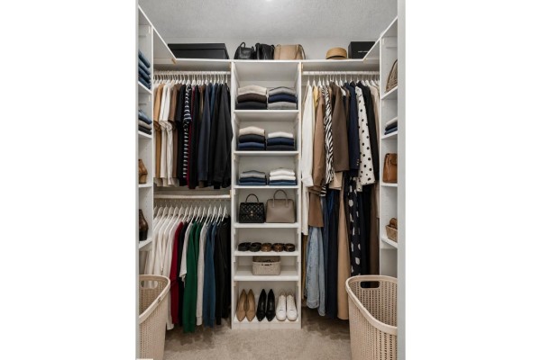 Walk-in closet with white shelves, hanging rods filled with colorful clothes, shoes, and handbags. - #21 15151 43 St Nw Nw, Edmonton