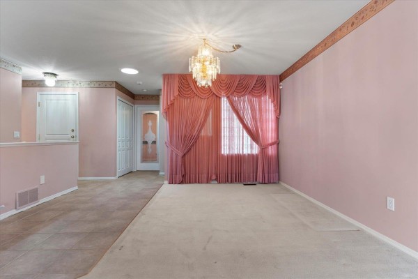 Interior view of a room with pink walls, a large pink curtain, and a chandelier. - 21 3902 Latimer Street, Abbotsford