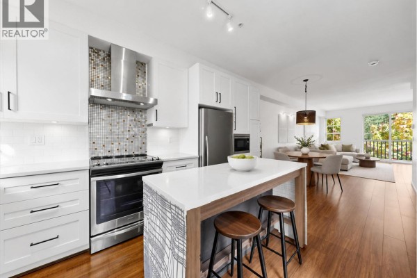 Kitchen with white cabinets, stainless steel appliances, and island with seating. - 21 433 Seymour River Place, North Vancouver