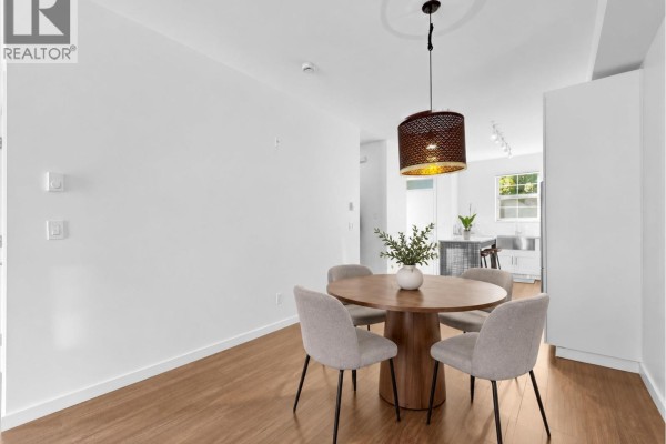 Dining area with round wooden table, four chairs, and pendant light. - 21 433 Seymour River Place, North Vancouver