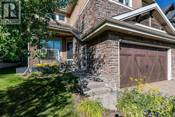 Close-up of the stone facade and entrance of a two-story home with a paved driveway. - 21 Ascot Crescent Sw, Calgary