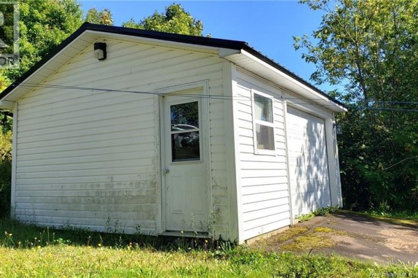 Front of the detached white garage with a large roll-up door and a side entrance. - 21 Clifford Street, Mcadam