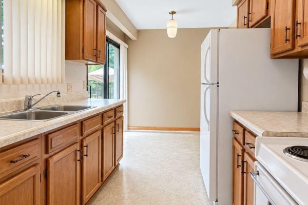 Kitchen with light wood cabinets, stainless steel sink, white refrigerator, and view of a dining area. - 21 Croydon Drive, St  Catharines