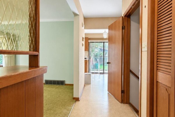 Hallway showing a wood door, wood paneling, and a view into the kitchen and dining area. - 21 Croydon Drive, St  Catharines