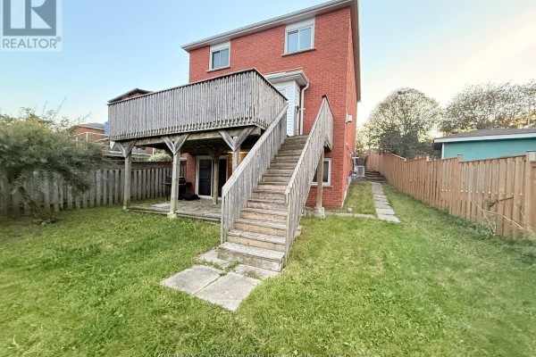View through sliding glass door to a paved patio and fenced backyard in winter. - 21 Fernbank Place, Whitby