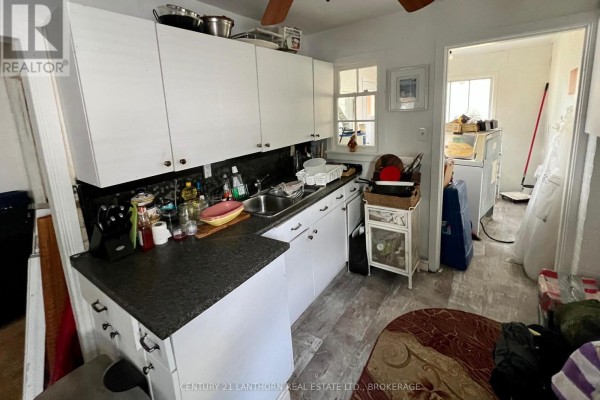 A small kitchen with white cabinets, black speckled countertops, and linoleum flooring. - 21 First Avenue, Kingston