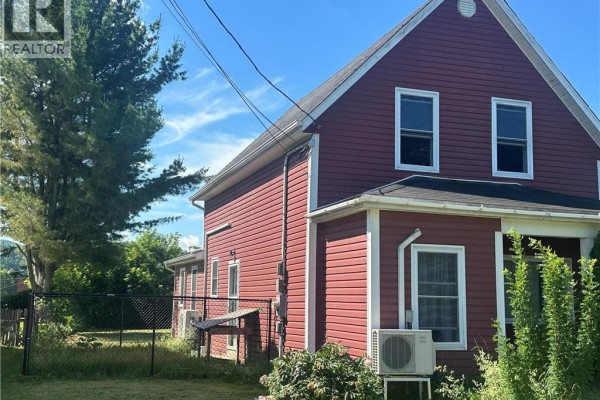 Side exterior of a two-story red house with red siding, white trim, and air conditioning units. - 21 Fort Road, Perth Andover