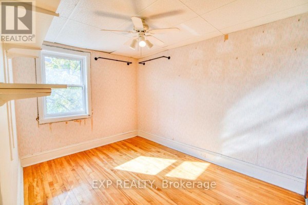 Bedroom with wood floors, a ceiling fan, and a window overlooking trees. - 21 Garrison Street, Ottawa