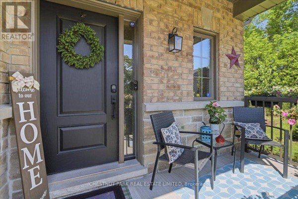 Close-up of the townhouse front door with a wreath, welcome sign, and porch seating. - 21 Gord Matthews Way, Uxbridge