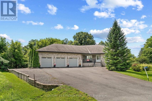 Side view of a stone ranch house with a three-car garage and driveway. - 21 Holly Drive, Edwardsburgh/cardinal