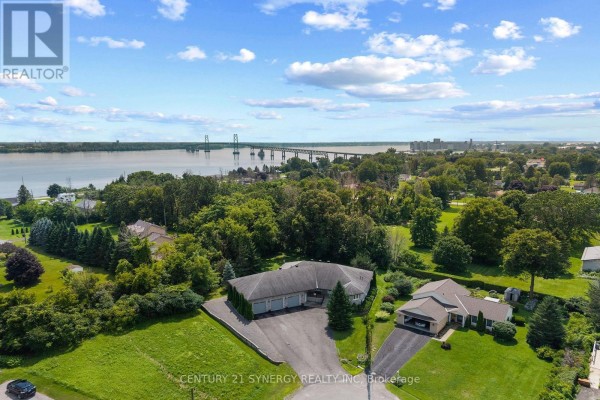 Aerial view showing the ranch house, neighbouring properties, and a distant bridge over a river. - 21 Holly Drive, Edwardsburgh/cardinal