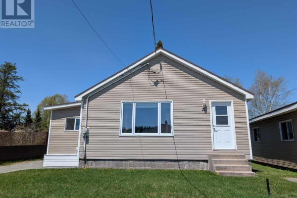Kitchen with wood cabinets, a white stove, and a small dining table. - 21 Joliet St, Wawa