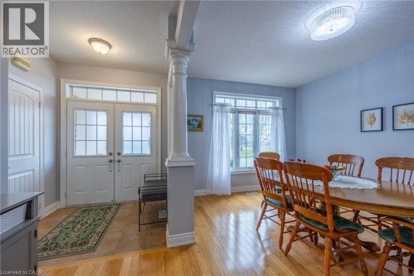 Dining room with a wooden table and chairs, open to a living room with a fireplace. - 21 Kelly Drive, Port Dover