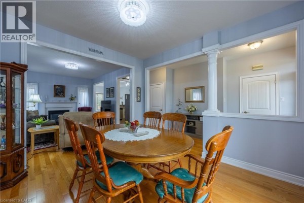 Living room with a sofa, armchair, fireplace, and large area rug on hardwood floors. - 21 Kelly Drive, Port Dover