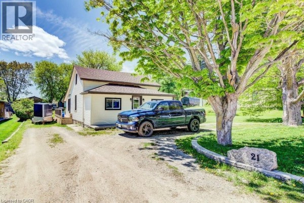 Second attic bedroom with sloped ceiling, two beds, and wooden flooring, decorated with personal items. - 21 Main Street W, Drayton