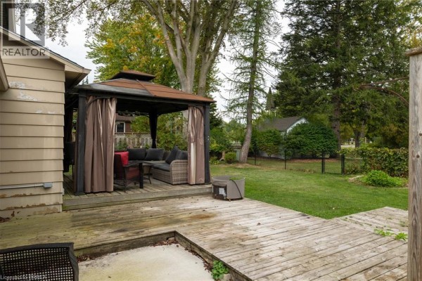 Wooden deck with a gazebo and outdoor seating overlooking a green backyard with trees. - 21 Mccall Street, Simcoe